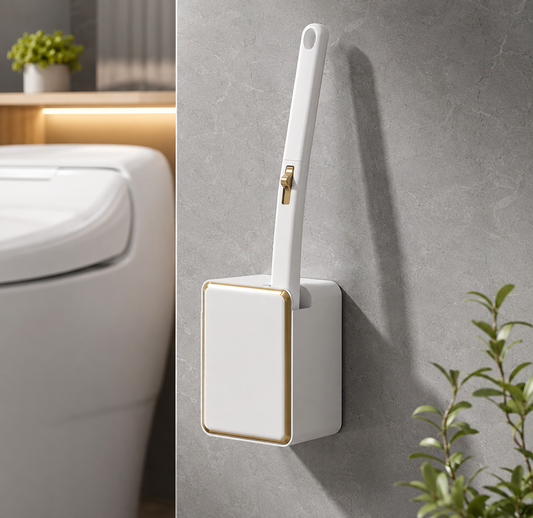 White toilet brush handle stored in a gold-trimmed wall-mounted holder beside a toilet
