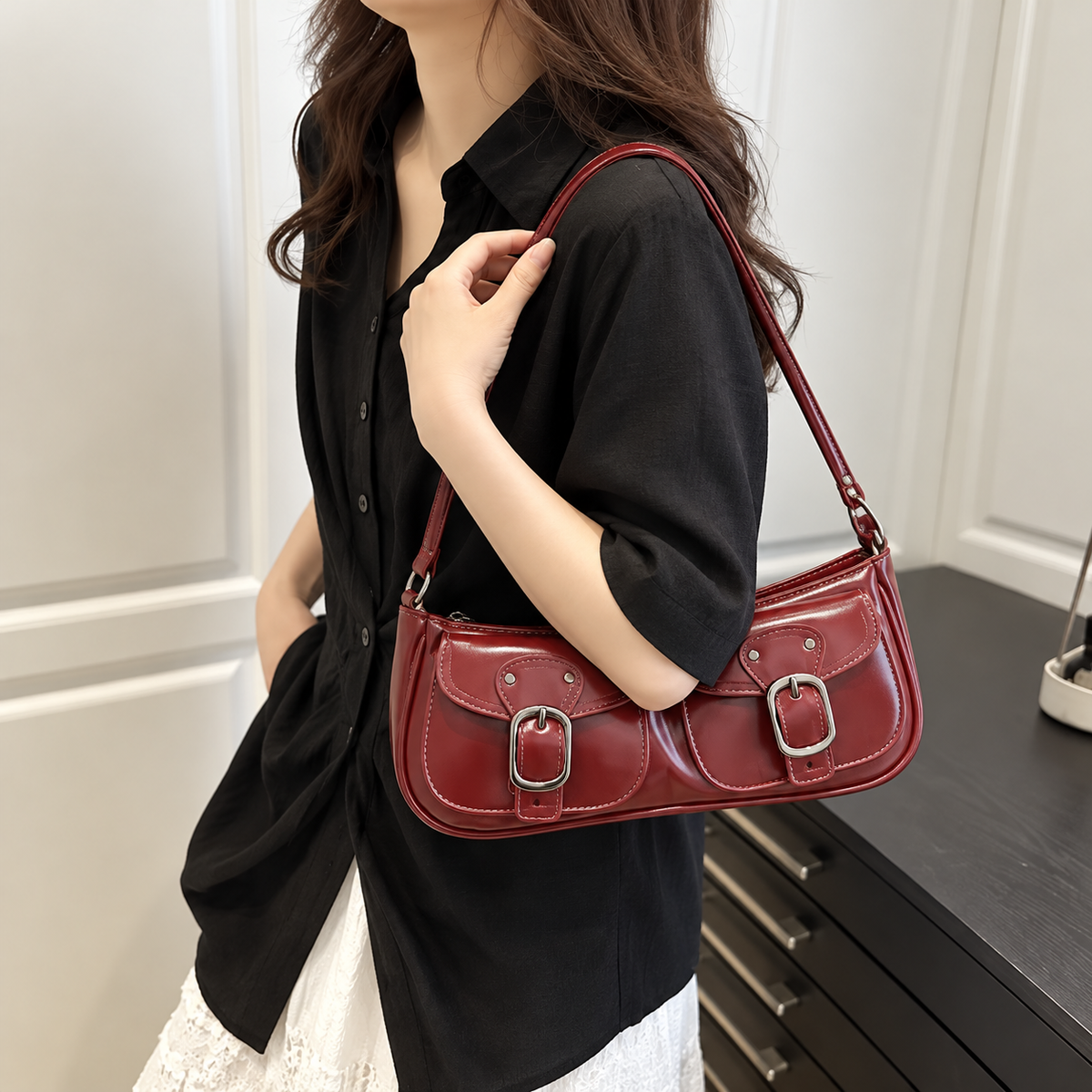 Woman carrying a wine red PU leather shoulder bag with front buckle details over a black shirt