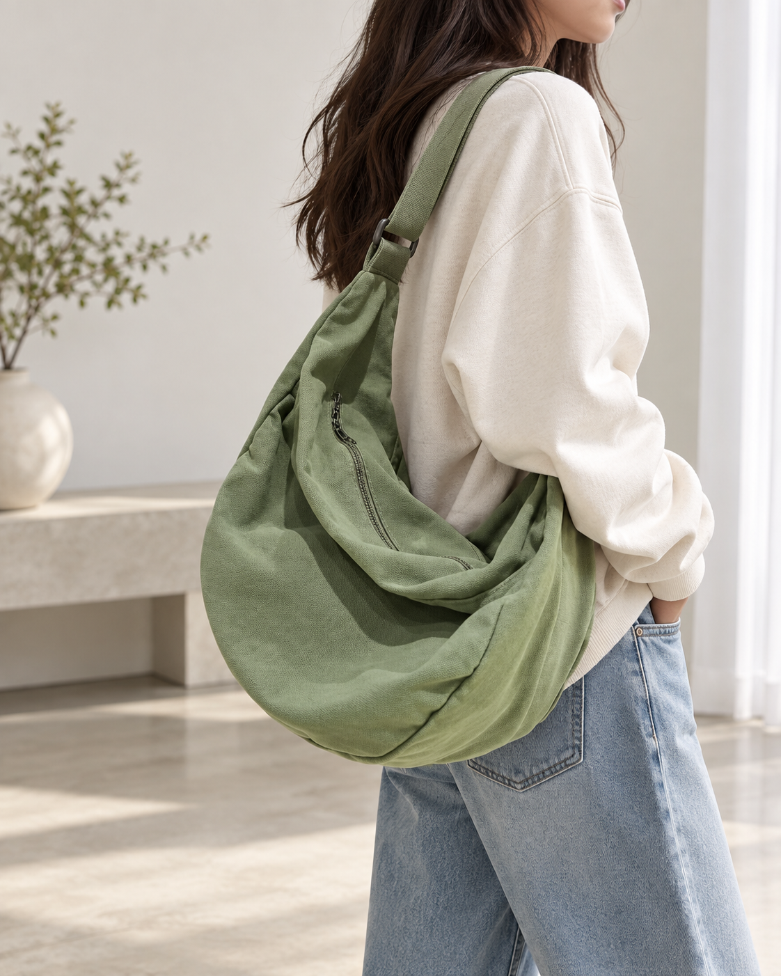 Woman wearing a green hobo shoulder bag with an adjustable strap and zip closure