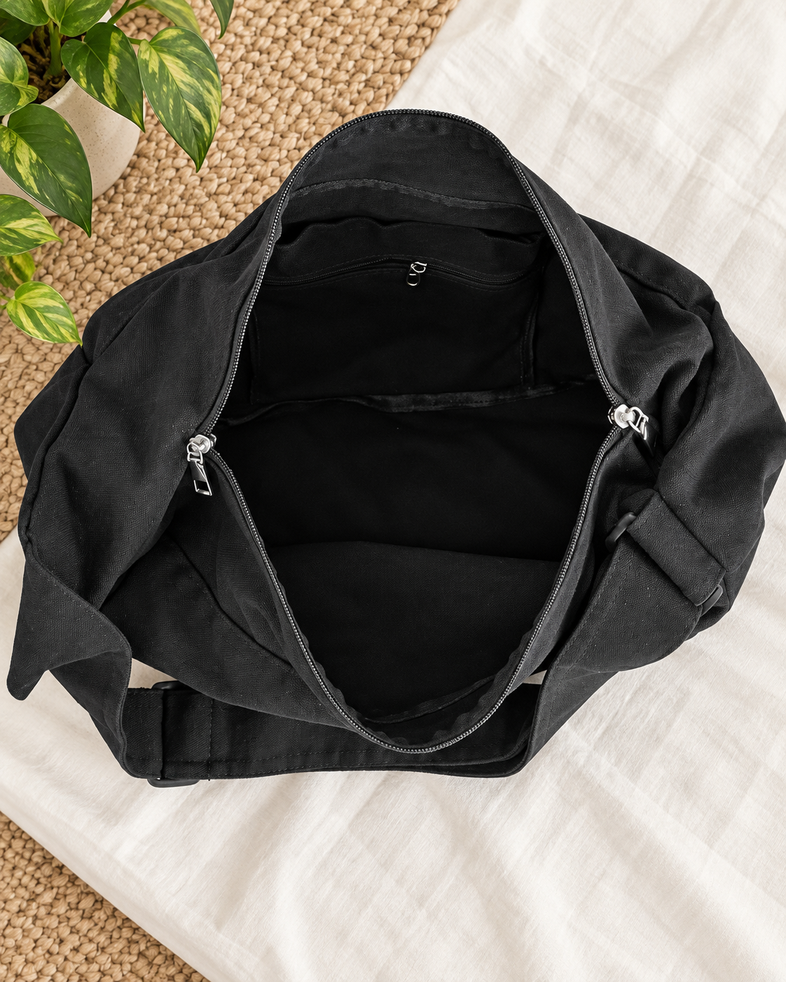 Open black shoulder bag showing its main compartment, fabric lining and interior zip pocket